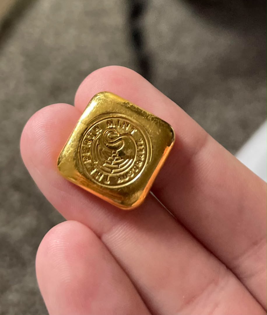 Small stamped gold ingot held between fingers
